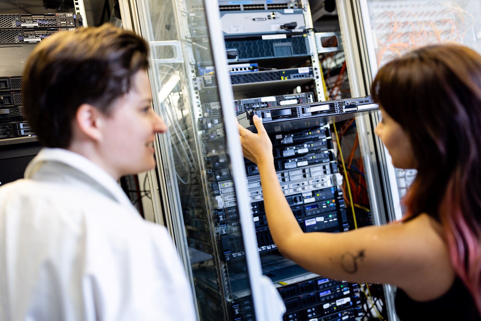 zwei Personen arbeiten an einem Serverschrank