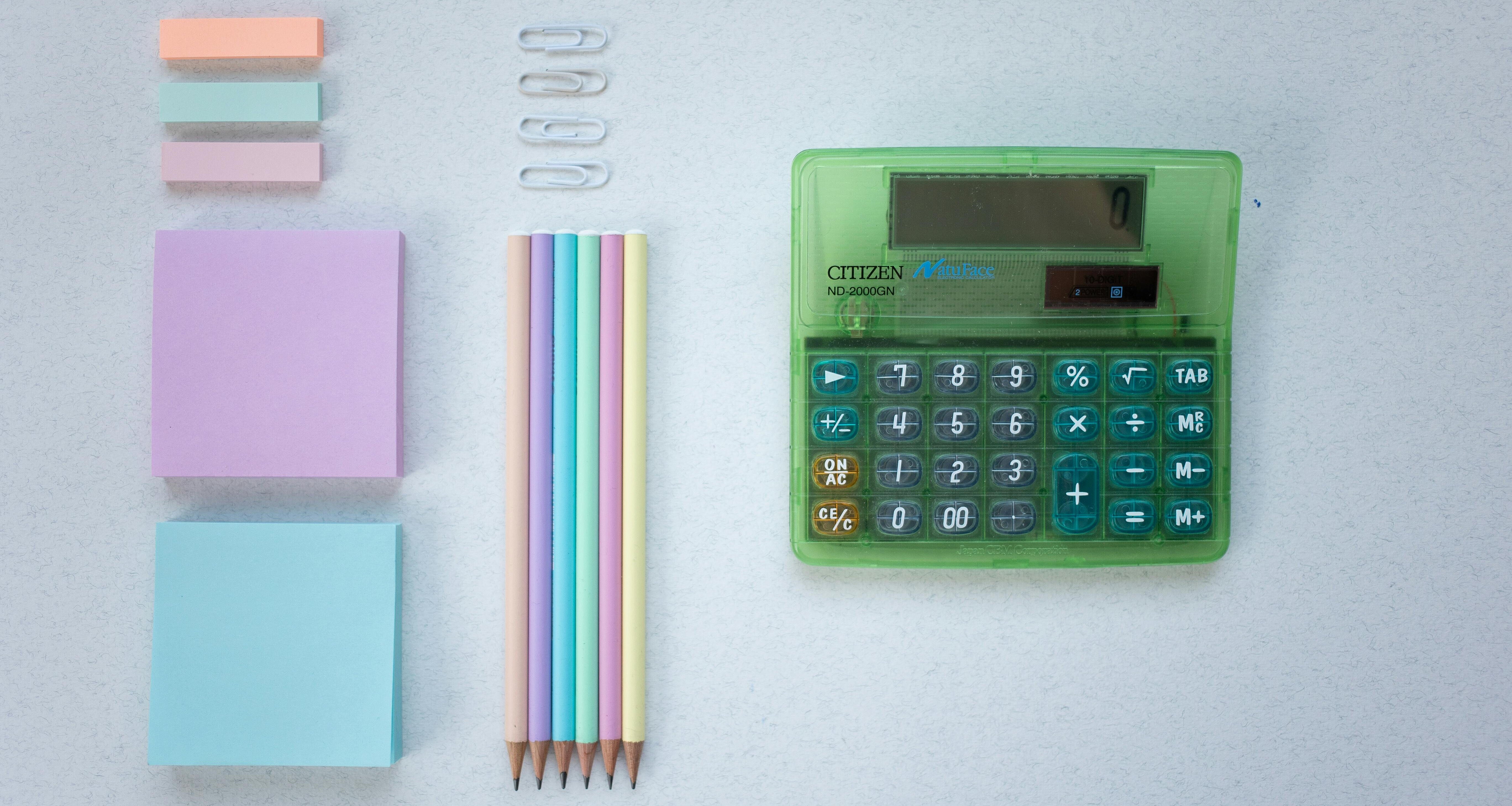 auf einer Unterlage angeordnetes Büromaterial, u.a. ein Taschenrechnerund Post-its