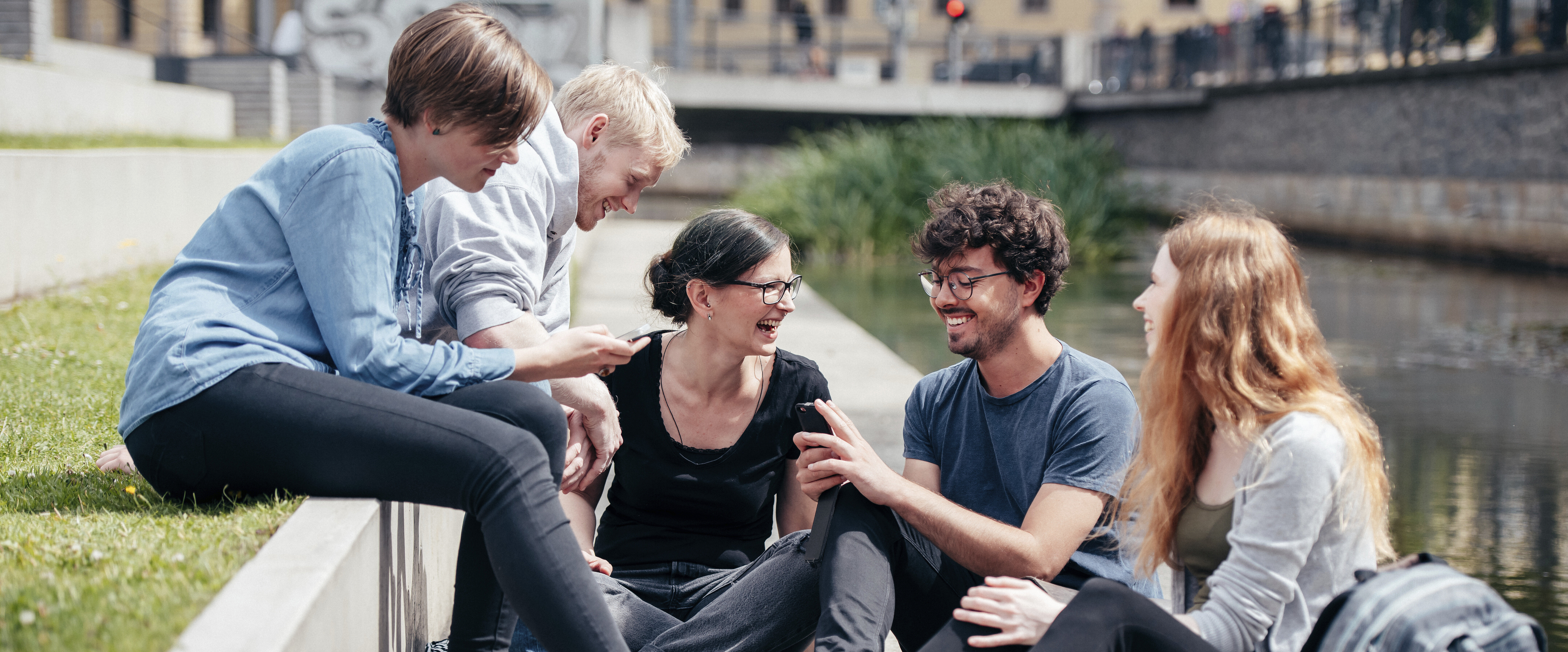 eine Gruppe junger Menschen unterhält sich fröhlich im Freien