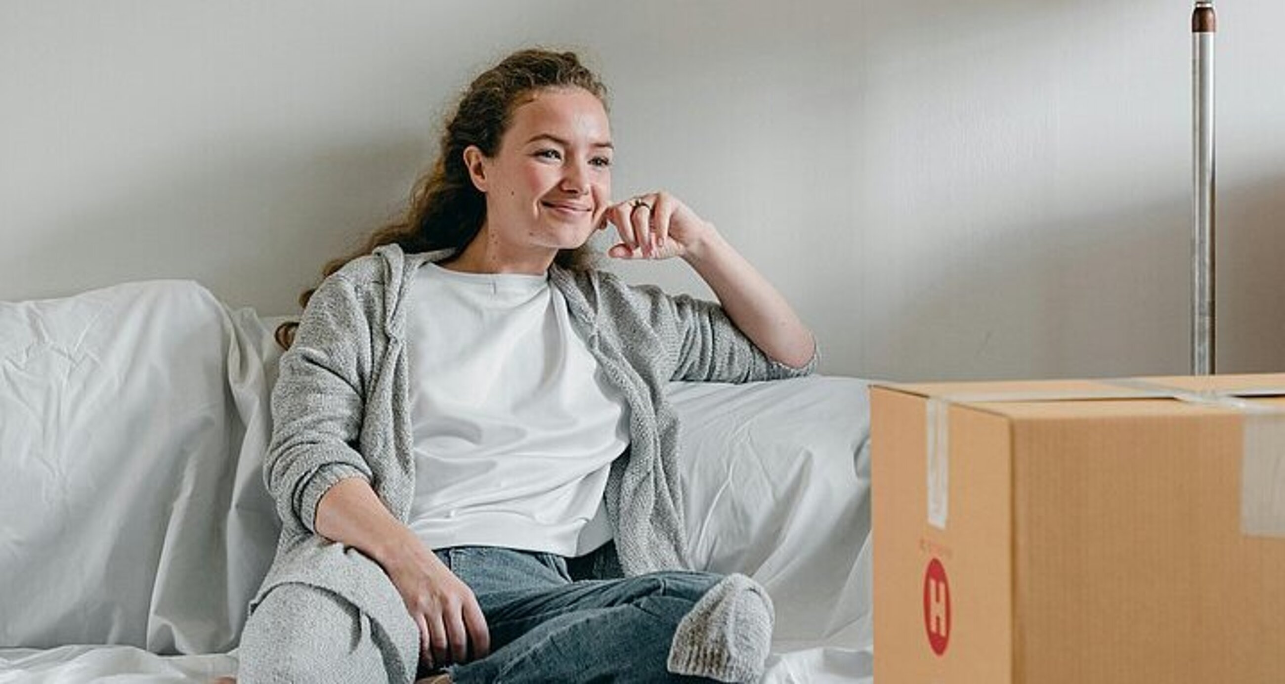 Frau auf Sofa inmitten von Umzugskartons