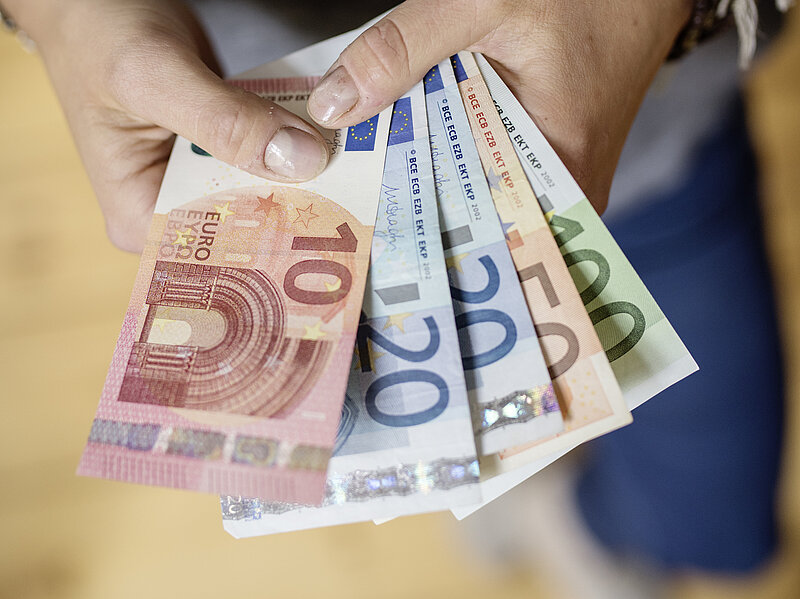 Eine Person hält Geldscheine in der Hand