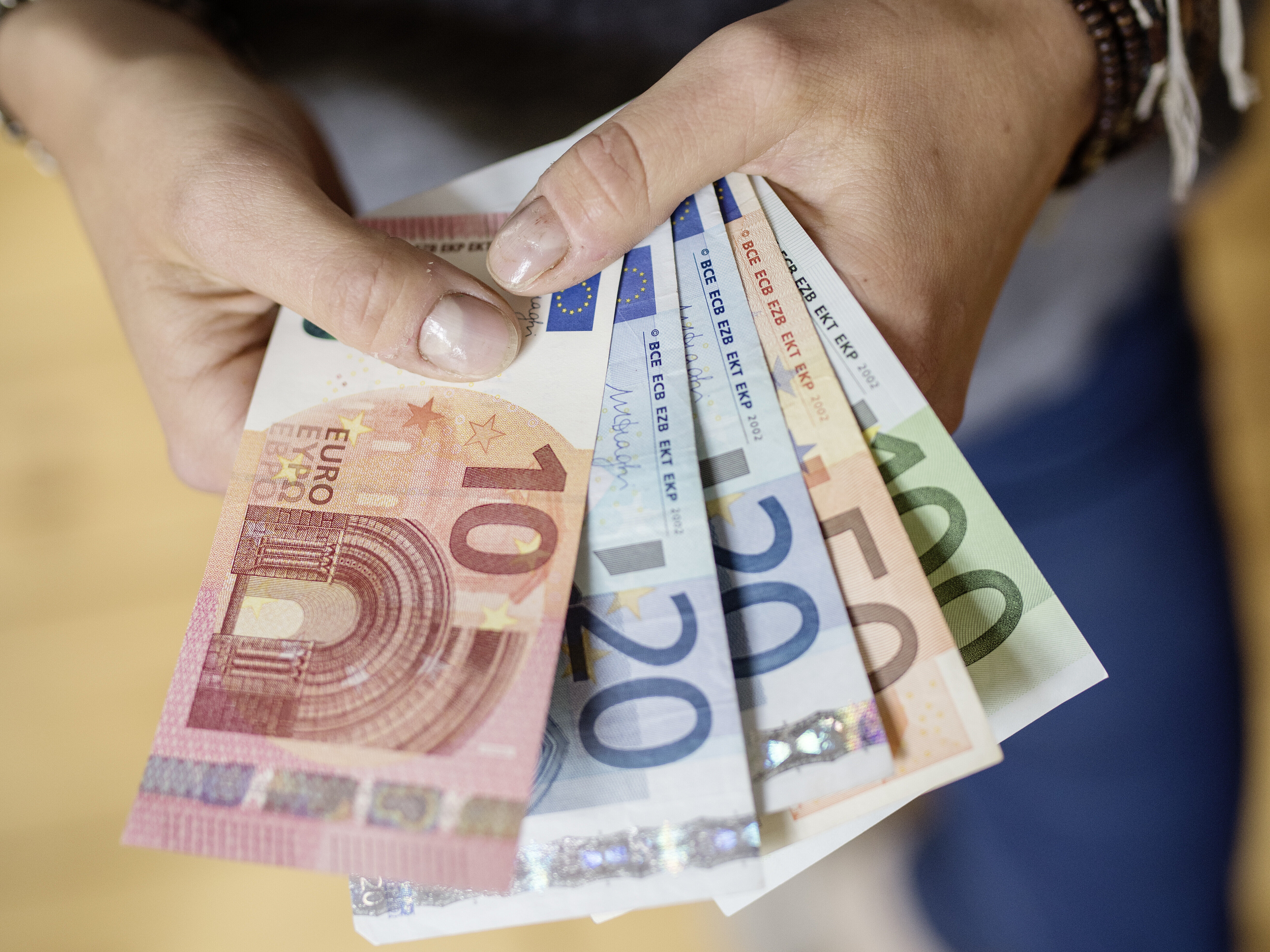 Eine Person hält Geldscheine in der Hand