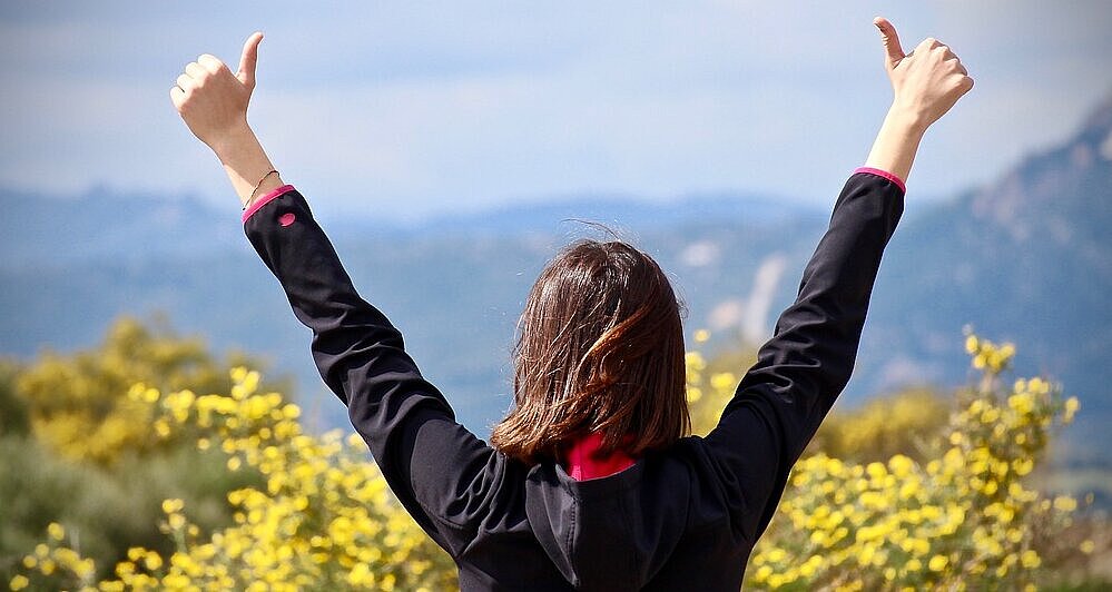 Rear view of a woman in nature with both thumbs up