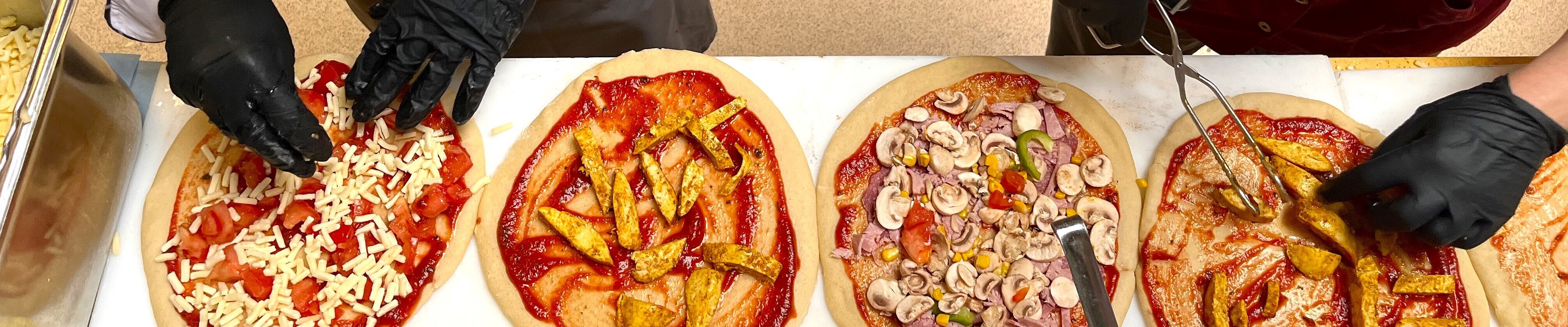 Zwei Personen belegen Pizzen