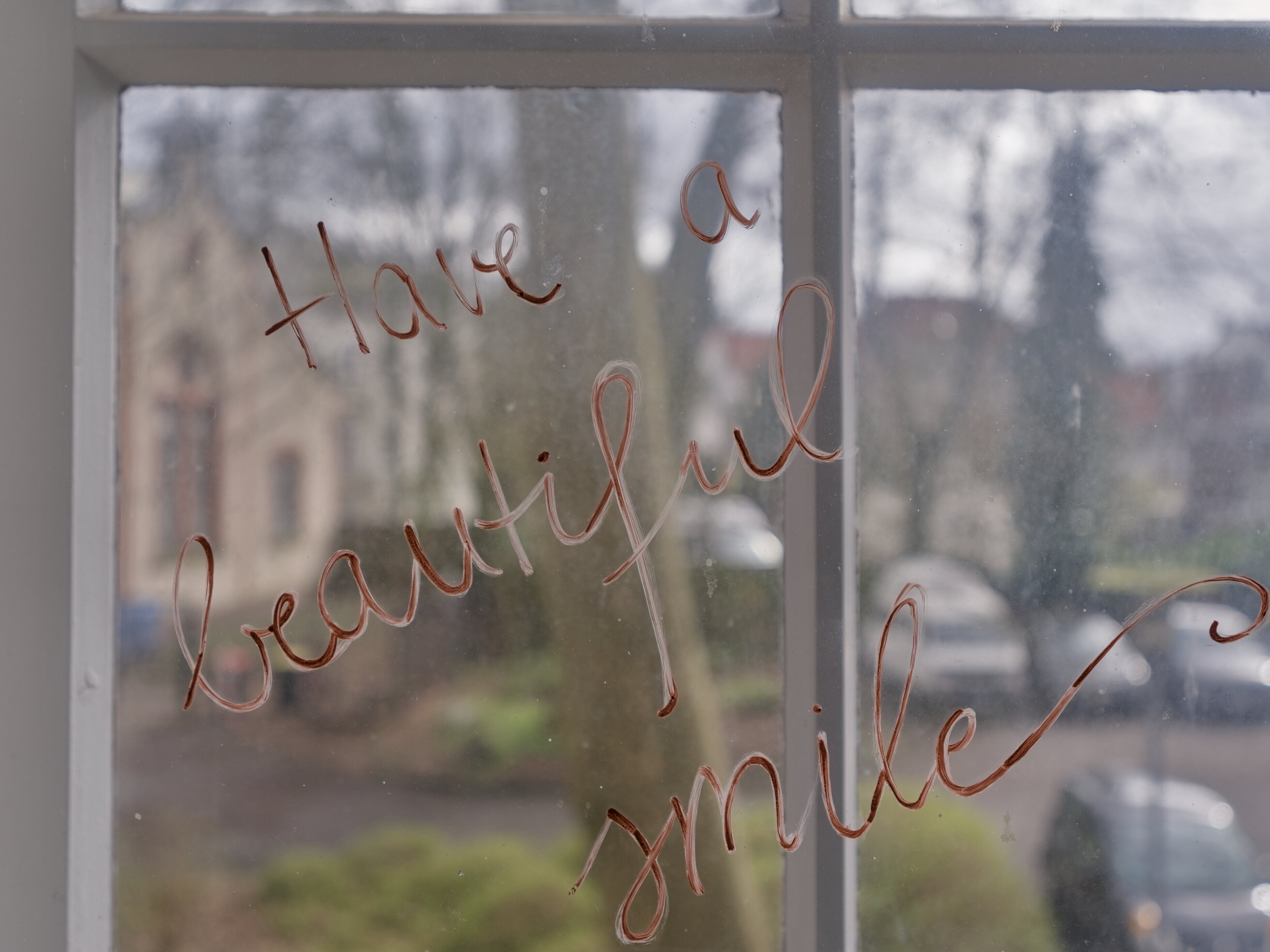 "Have a beautiful smile" geschrieben auf einem Fenster im Pferdemarkt 15b