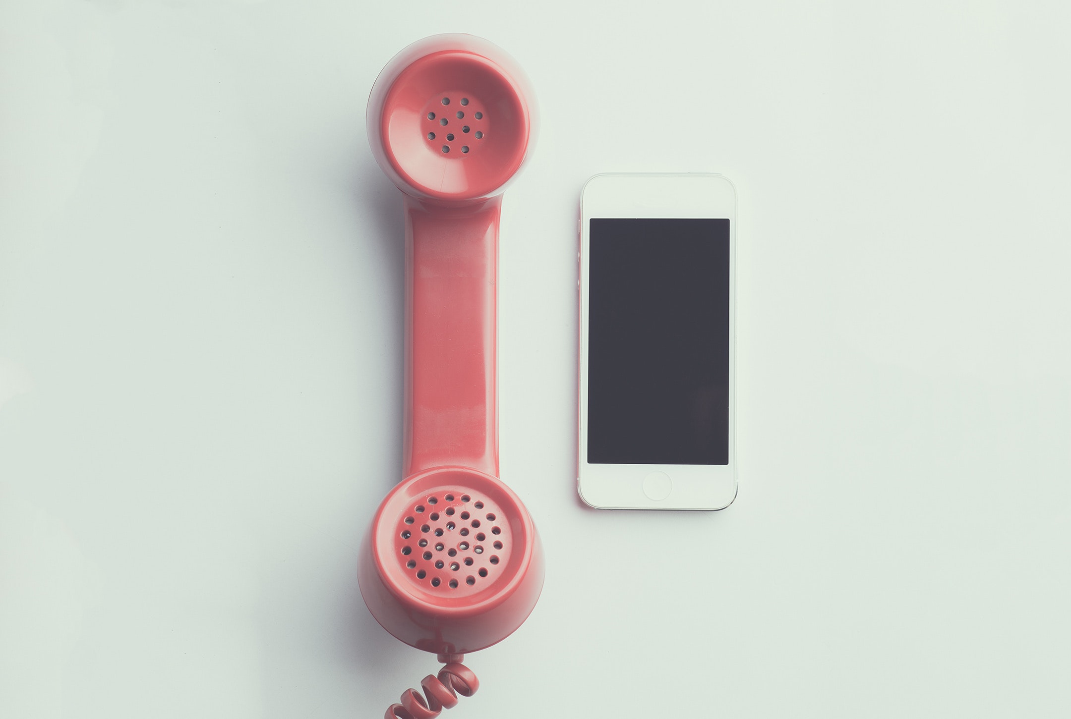 ein Smartphone neben einem altmodischen roten Telefonhörer